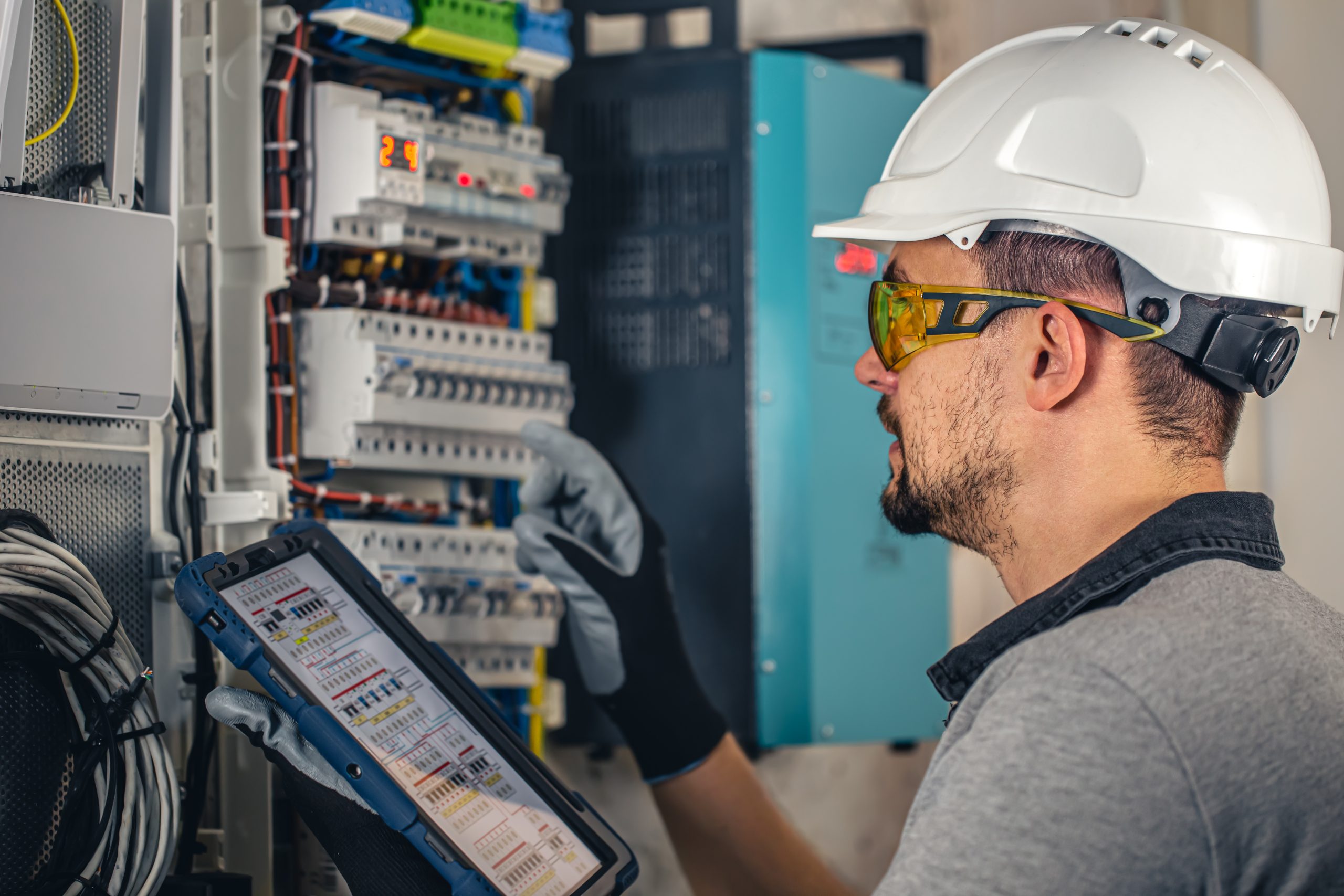 Man, an electrical technician working in a switchboard with fuses.